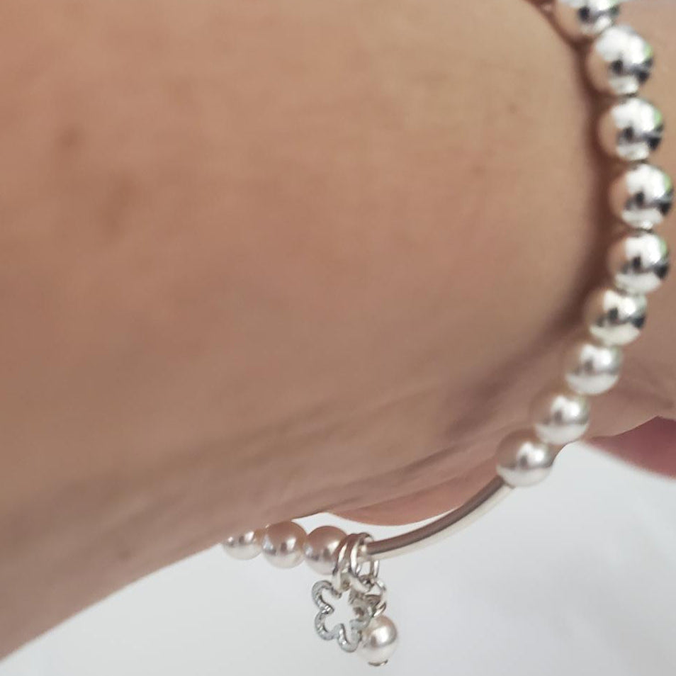 Silver bracelet on a wrist with a plain background
