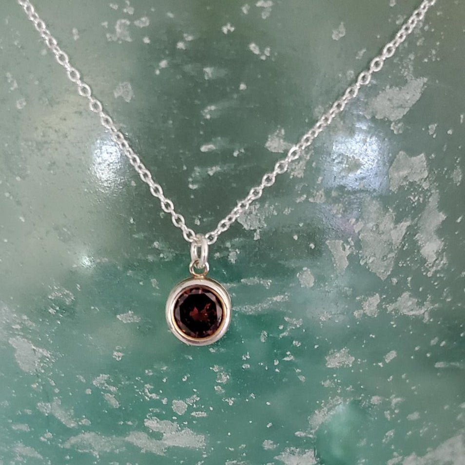 Necklace with a dark gemstone pendant on a textured green surface