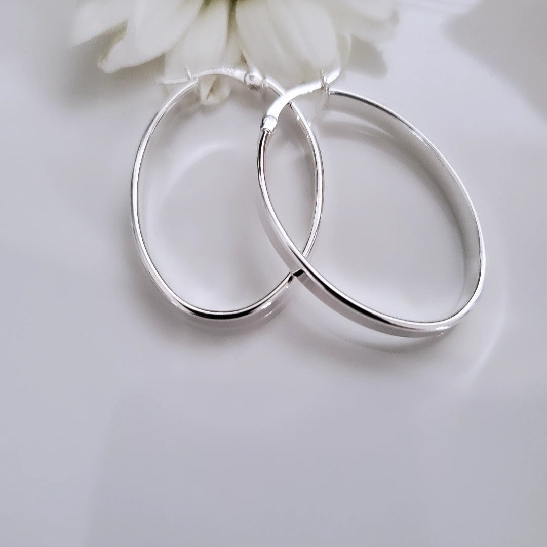 Introducing my Flat Oval Sterling Silver Hoops: timeless and versatile for everyday elegance. The smooth, flat oval shape adds polish to any outfit, perfect for various occasions with comfort and style. Ideal for solo statements or layered looks, these hoops embody effortless sophistication, maintained by regular cleaning and proper storage.