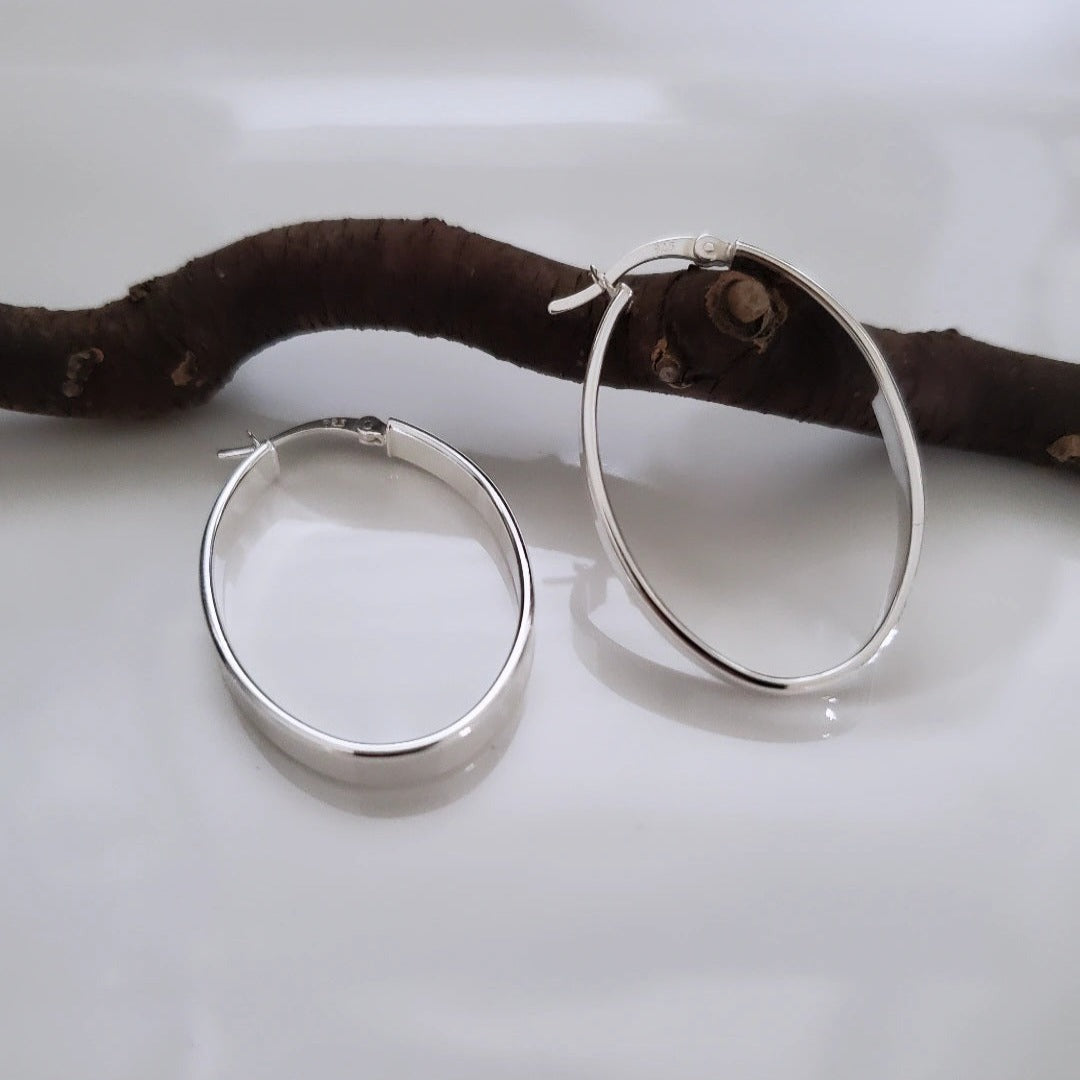 Introducing my Flat Oval Sterling Silver Hoops: timeless and versatile for everyday elegance. The smooth, flat oval shape adds polish to any outfit, perfect for various occasions with comfort and style. Ideal for solo statements or layered looks, these hoops embody effortless sophistication, maintained by regular cleaning and proper storage.