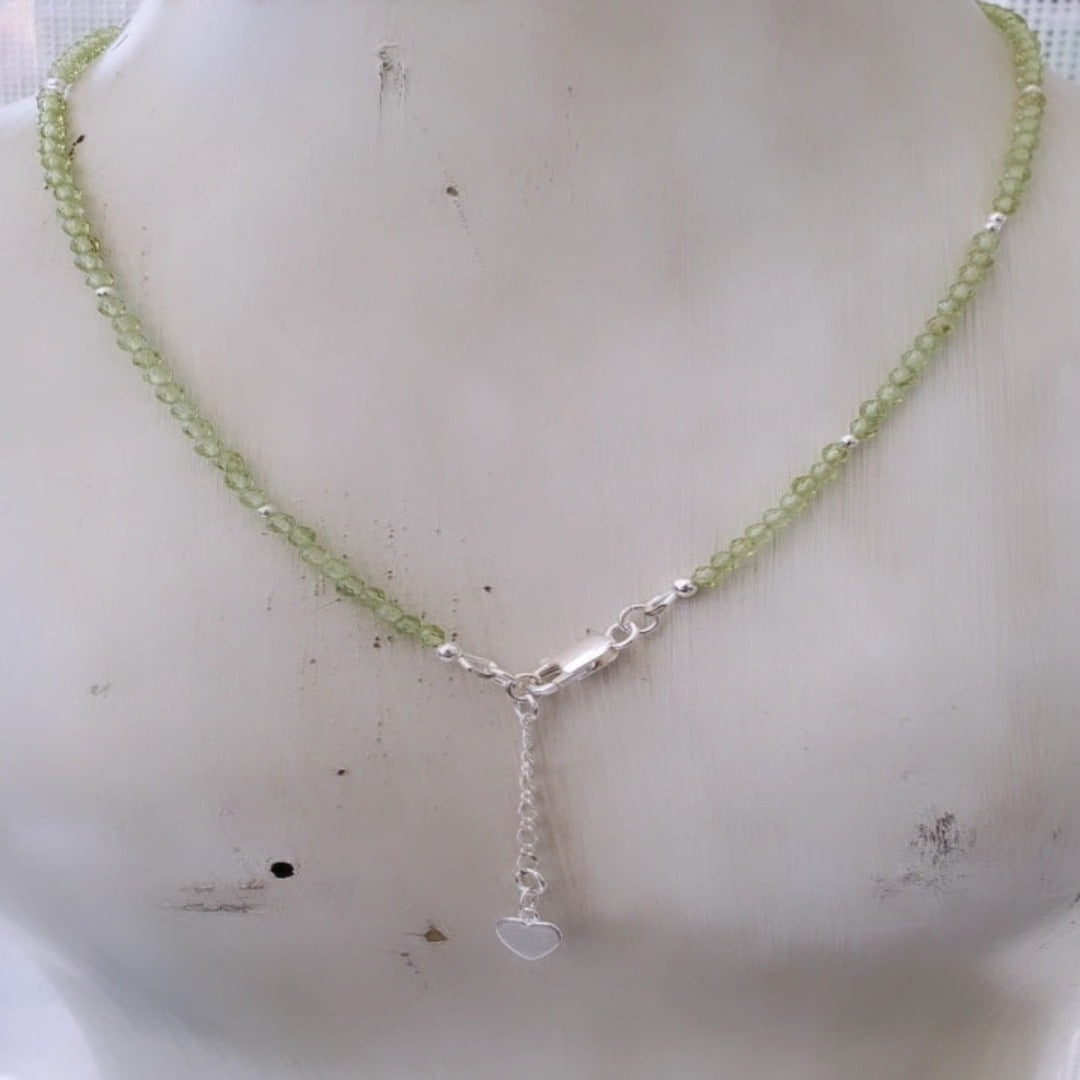 Picture of Peridot Gemstone Layering Necklace with Heart Charm. This necklace features 3.0mm micro-faceted peridot gemstones and a heart charm, symbolizing love and compassion. Its delicate design adds a touch of sophistication and elegance to any outfit, perfect for both formal and casual occasions.