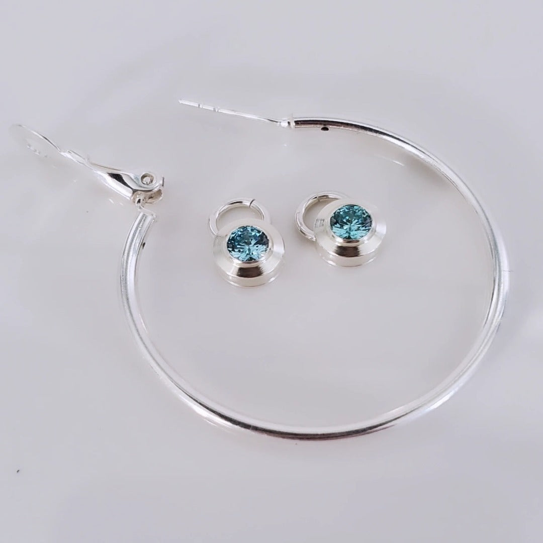 Introducing elegant 4mm Aquamarine and Peridot Sterling Silver Bezel Set Hoop Charms. Featuring genuine aquamarine and peridot gemstones, these charms add sophistication and natural beauty to any ensemble. With serene blue and vibrant green hues, they offer a timeless yet modern appeal. Perfect for elevating everyday style with a touch of elegance.