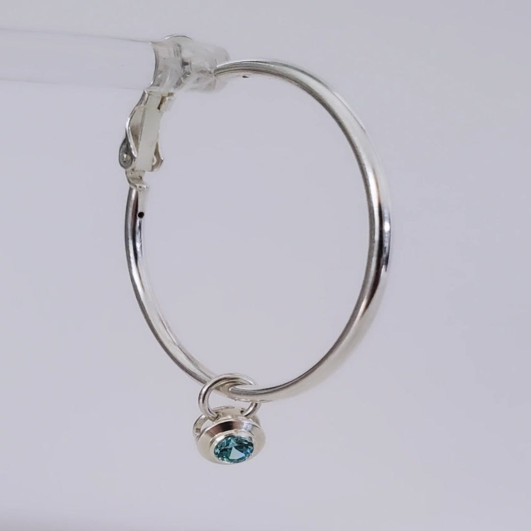 Introducing elegant 4mm Aquamarine and Peridot Sterling Silver Bezel Set Hoop Charms. Featuring genuine aquamarine and peridot gemstones, these charms add sophistication and natural beauty to any ensemble. With serene blue and vibrant green hues, they offer a timeless yet modern appeal. Perfect for elevating everyday style with a touch of elegance.