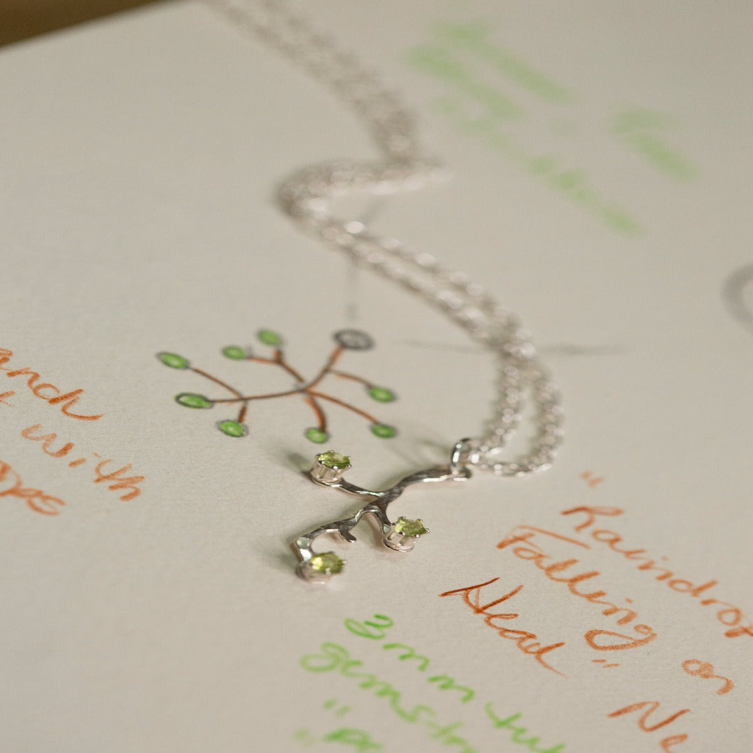 Image of a Sterling Silver Spring Tree Bud Branch Necklace, symbolizing power, durability, and perpetual growth. Inspired by John Muir's quote, "I venture into the forest, to release my thoughts and discover my inner self," this necklace represents a deep connection to nature and the endless possibilities that lie ahead. The design features intricately crafted branches extending upwards, capturing the essence of growth and resilience.