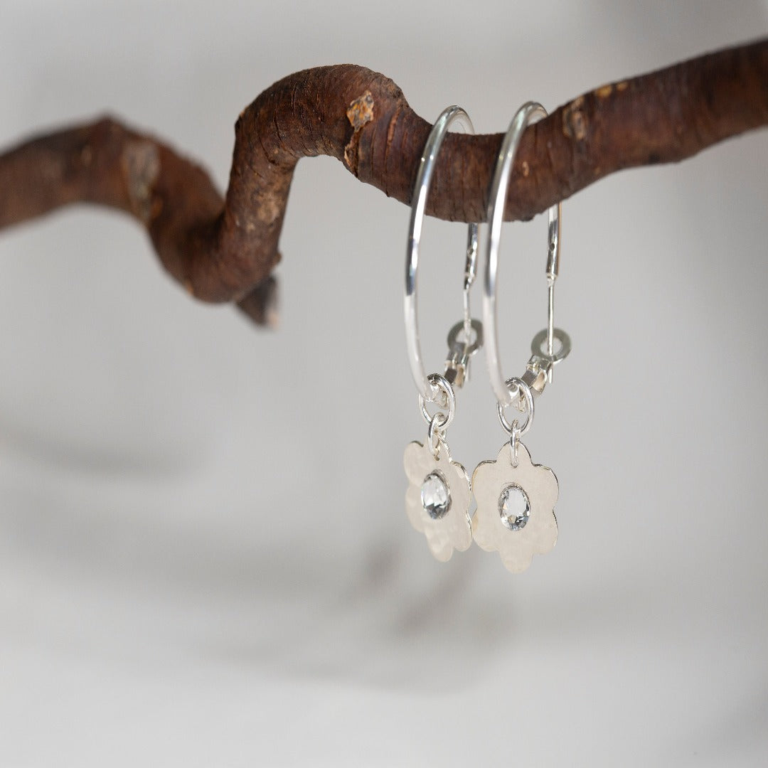 Sterling Silver Hoop Moodmaker Earrings featuring daisy charms and Swarovski crystal cubic zirconia flatbacks. These versatile earrings offer two looks in one with removable charms. The classic hoop design is perfect for everyday wear or special occasions, adding a touch of elegance and joy to your look.