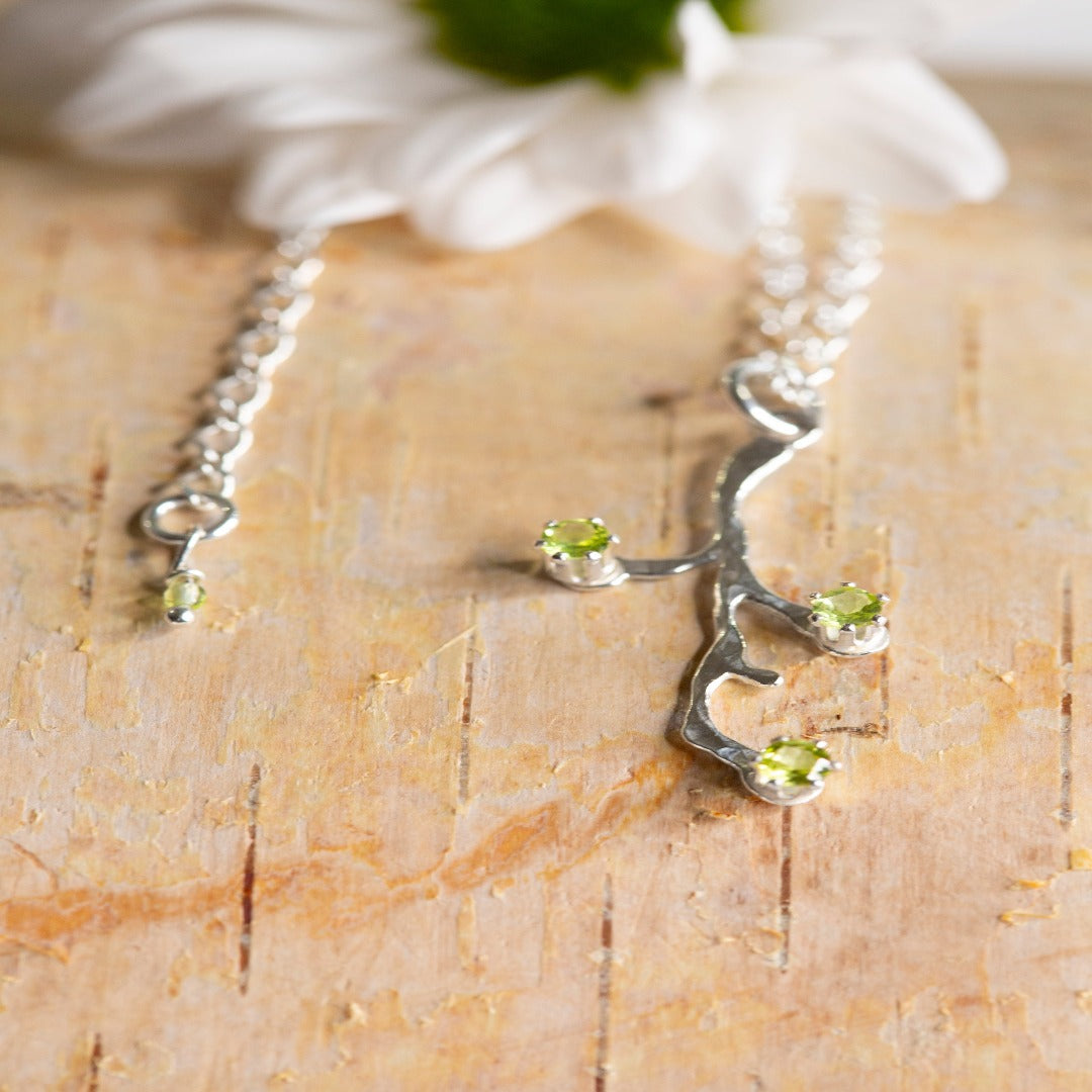 Image of a Sterling Silver Spring Tree Bud Branch Necklace, symbolizing power, durability, and perpetual growth. Inspired by John Muir's quote, "I venture into the forest, to release my thoughts and discover my inner self," this necklace represents a deep connection to nature and the endless possibilities that lie ahead. The design features intricately crafted branches extending upwards, capturing the essence of growth and resilience.