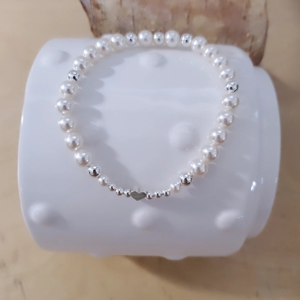 Swarovski Pearl Harmony Heart Bracelet featuring a symphony of white Swarovski pearls and sterling silver beads, accented with a sweet heart charm. This bracelet embodies nature's melody, inviting harmony and joy. Crafted with passion and inspired by nature, it captures timeless elegance and the beauty of the natural world.