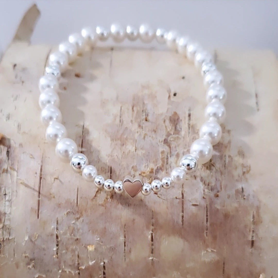 Swarovski Pearl Harmony Heart Bracelet featuring a symphony of white Swarovski pearls and sterling silver beads, accented with a sweet heart charm. This bracelet embodies nature's melody, inviting harmony and joy. Crafted with passion and inspired by nature, it captures timeless elegance and the beauty of the natural world.