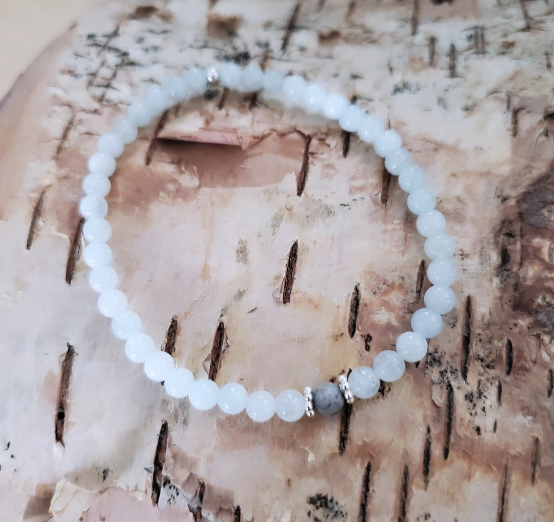 Introducing my Aquamarine Gemstone Sea of Blue Bracelet, embodying timeless elegance and serenity. The 4mm Aquamarine gemstones capture the ocean's tranquility, complemented by Sterling Silver daisy spacers for added sophistication. A 4mm matte Picture Jasper gemstone adds grounding qualities. Wear it solo or mix and match with other Plein De Vie Jewelry bracelets for a unique look.