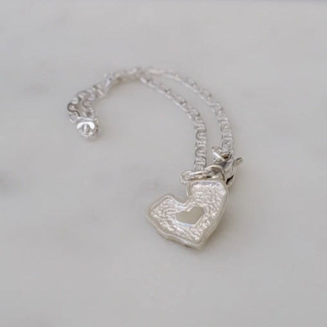 Introducing my Sterling Silver Half Flat Oval Mariner Curb Bracelet, a timeless 7-inch piece exuding elegance and charm. Crafted with half flat oval links and a double heart charm, it adds a touch of love and sophistication. Wear it solo or layered with other Plein De Vie Jewelry bracelets for a unique style. Elevate your look with this versatile bracelet from Plein De Vie Jewelry.