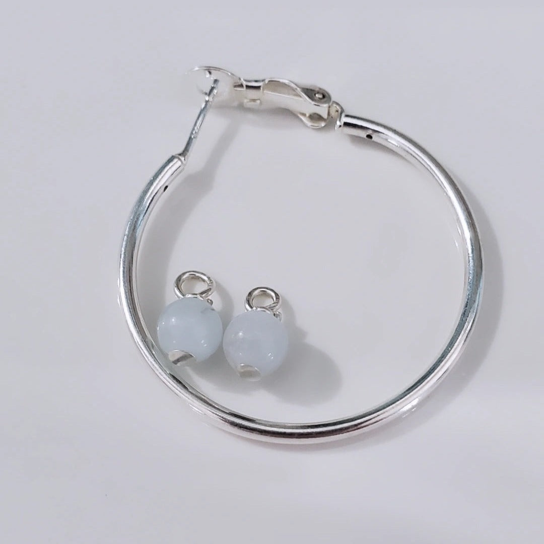 Introducing exquisite 6mm Genuine Round Aquamarine Sterling Silver Hoop Charms. Showcasing serene blue aquamarine gemstones set in sterling silver, these charms offer timeless sophistication and versatility. Perfect for everyday wear or special occasions, they add ethereal beauty and a touch of serenity to any jewelry collection.