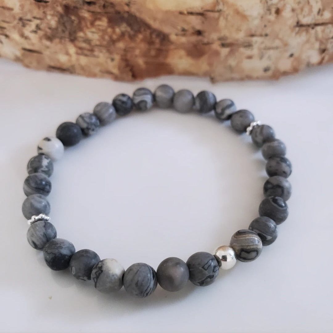 Introducing my Grounding 6mm Picture Jasper Gemstone Bracelet – a blend of timeless elegance and inner calm. Crafted with precision and passion, it adorns your wrist with luxury and serenity. Paired with Sterling Silver daisy spacers and a silver bead for sophistication. Wear it solo for refined elegance or mix and match for a unique stack. Elevate your style with Plein De Vie Jewelry.