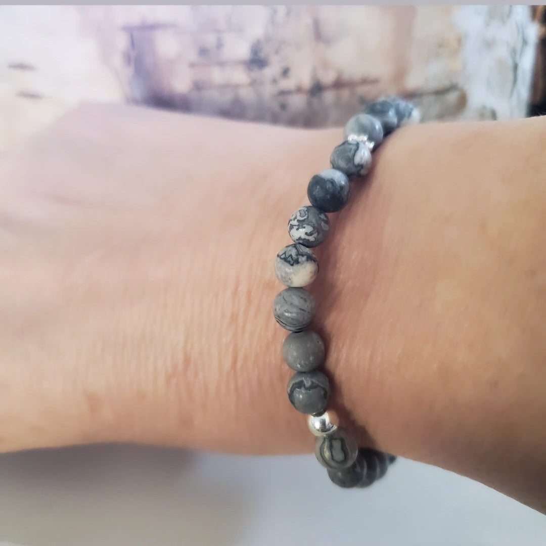 Introducing my Grounding 6mm Picture Jasper Gemstone Bracelet – a blend of timeless elegance and inner calm. Crafted with precision and passion, it adorns your wrist with luxury and serenity. Paired with Sterling Silver daisy spacers and a silver bead for sophistication. Wear it solo for refined elegance or mix and match for a unique stack. Elevate your style with Plein De Vie Jewelry.