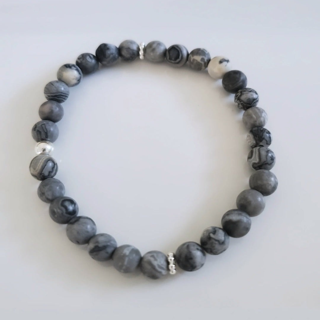 Introducing my Grounding 6mm Picture Jasper Gemstone Bracelet – a blend of timeless elegance and inner calm. Crafted with precision and passion, it adorns your wrist with luxury and serenity. Paired with Sterling Silver daisy spacers and a silver bead for sophistication. Wear it solo for refined elegance or mix and match for a unique stack. Elevate your style with Plein De Vie Jewelry.