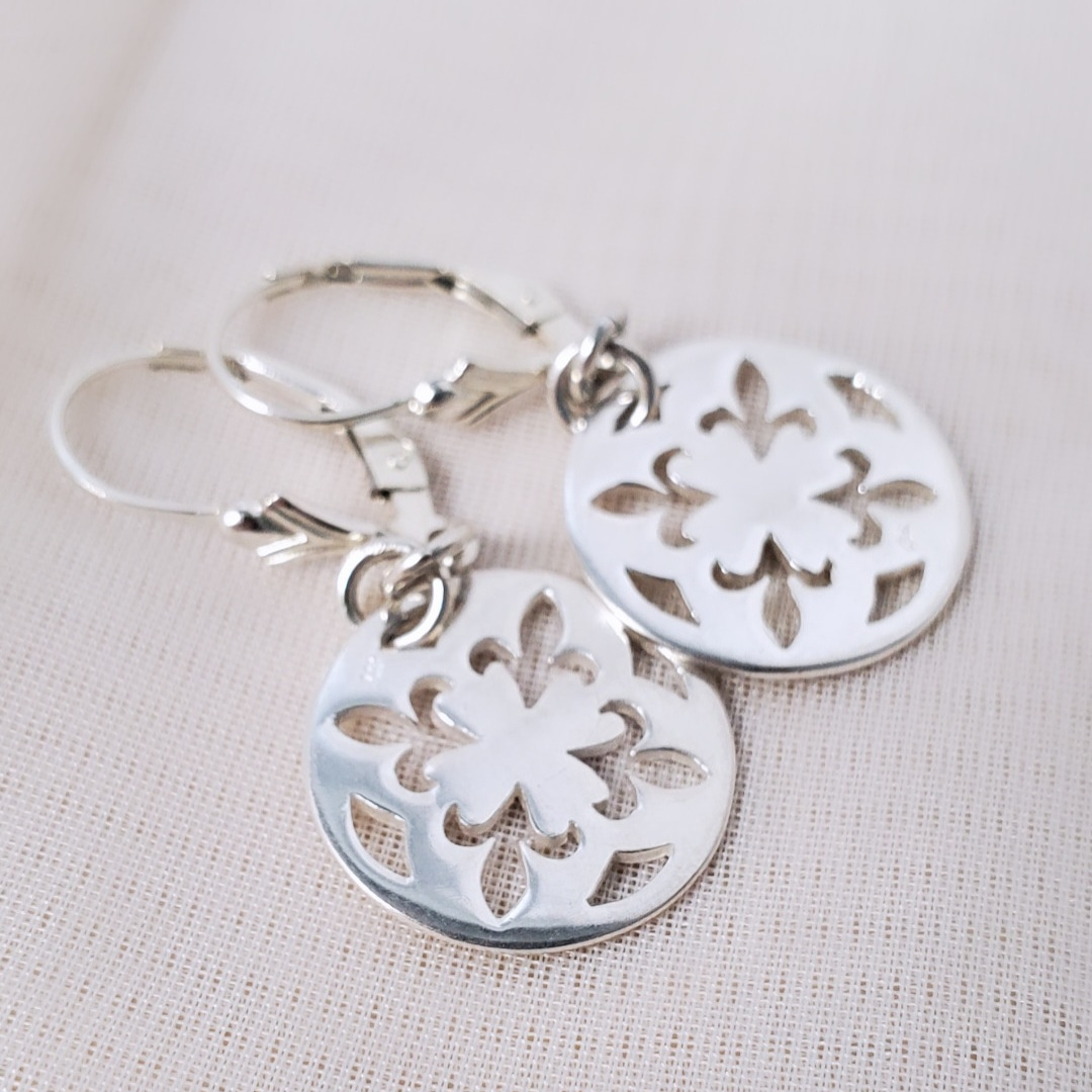 Introducing my Sterling Silver Leverback Fleur-de-lis Luxe Earrings: elegant and symbolic with a cut-out fleur-de-lis in a circle design. With a secure leverback closure, these earrings are inspired by French royalty, adding sophistication to any outfit. Perfect for both casual outings and formal events, they embody timeless elegance and cultural significance.