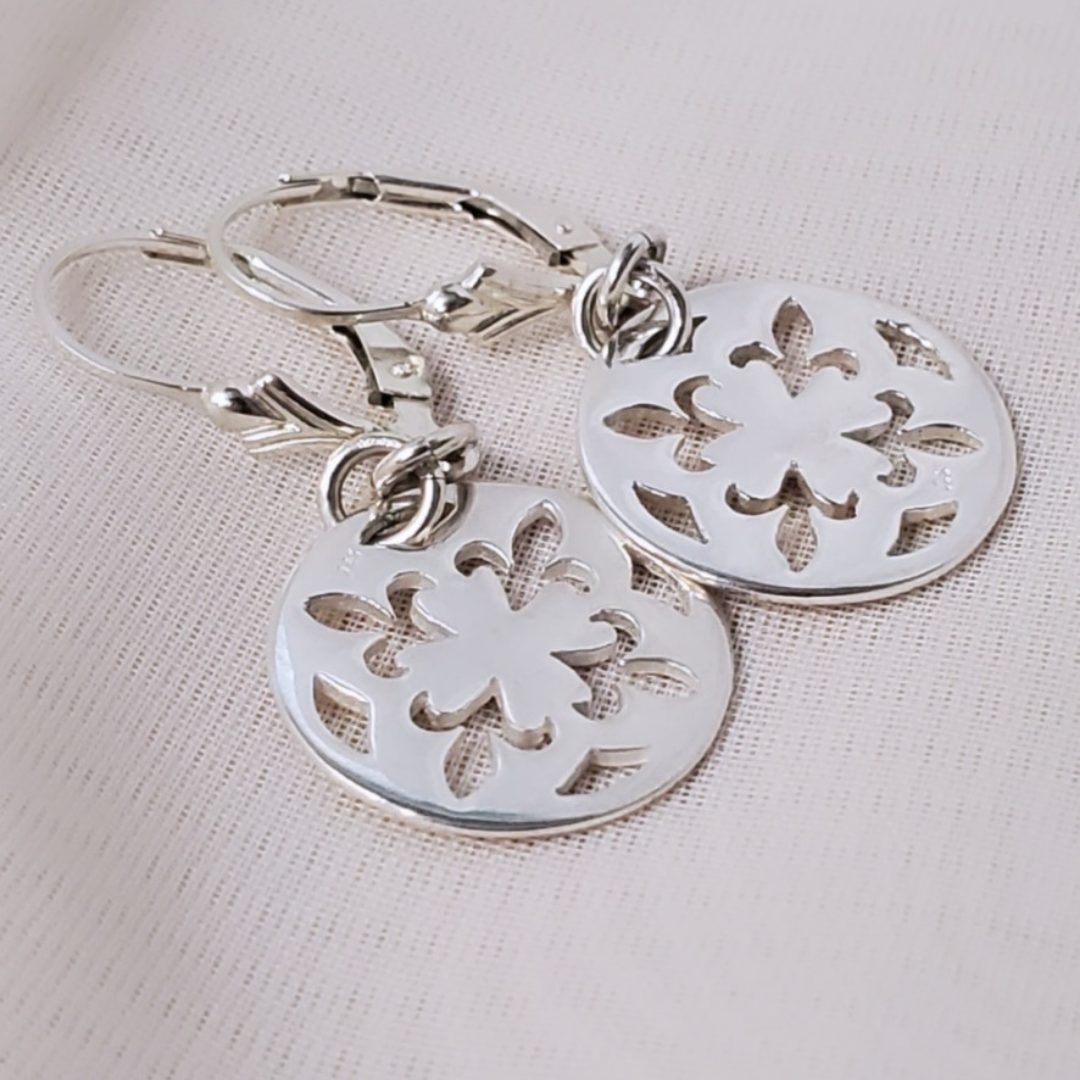 Introducing my Sterling Silver Leverback Fleur-de-lis Luxe Earrings: elegant and symbolic with a cut-out fleur-de-lis in a circle design. With a secure leverback closure, these earrings are inspired by French royalty, adding sophistication to any outfit. Perfect for both casual outings and formal events, they embody timeless elegance and cultural significance.