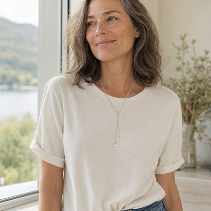 women in white tshirt with jeans smiling wearing the sterling silver pearl lariat necklace