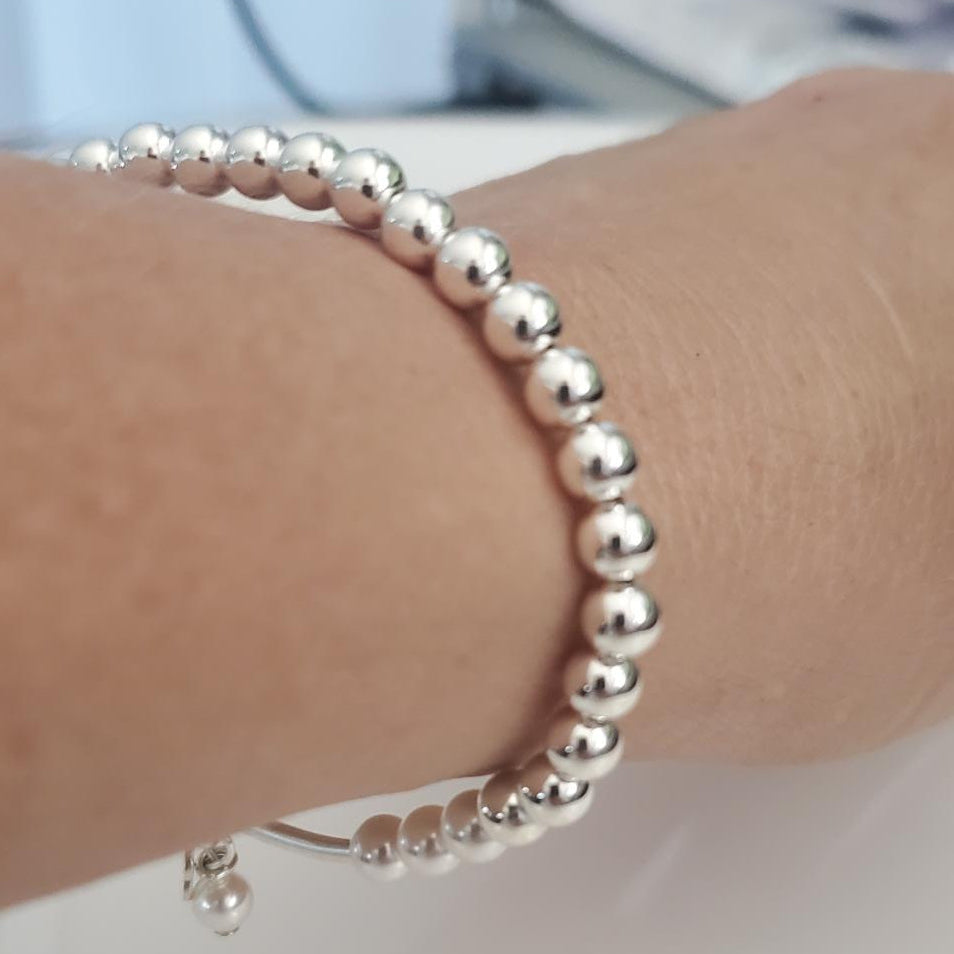 Silver beaded bracelet on a wrist with a blurred background