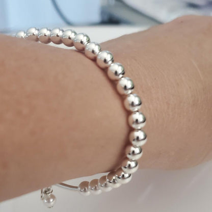 Silver beaded bracelet on a wrist with a blurred background