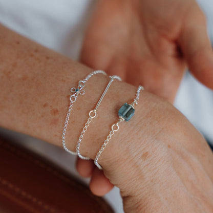 Sterling silver flower charm bracelet with a bezel set sparkling stone